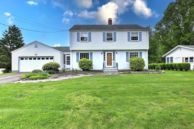423 Baldwin Ave, Meriden, CT 06450 - colonial home featuring a chimney, a garage, driveway, a front yard, and board and batten siding
