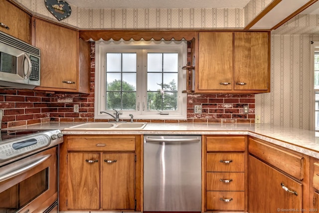 423 Baldwin Ave, Meriden, CT 06450 - kitchen featuring stainless steel appliances, wallpapered walls, a sink, brown cabinets, and healthy amount of natural light