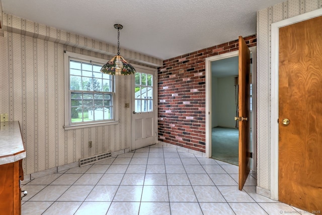423 Baldwin Ave, Meriden, CT 06450 - unfurnished dining area featuring a textured ceiling, wallpapered walls, brick wall, and light tile patterned flooring