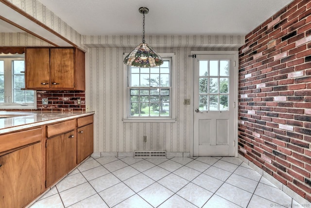 423 Baldwin Ave, Meriden, CT 06450 - kitchen featuring wallpapered walls, brown cabinetry, light tile patterned floors, light countertops, and pendant lighting