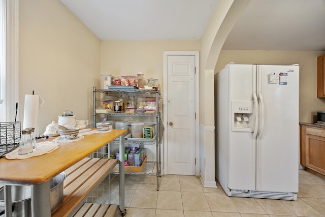 124 Jordan Ln, Wethersfield, CT 06109 - kitchen with white fridge with ice dispenser, arched walkways, light tile patterned floors, and brown cabinetry
