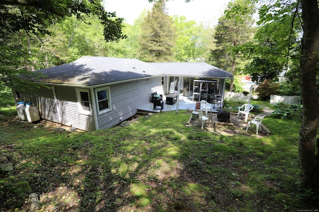 18 Totoket Rd, Waterford, CT 06375 - rear view of house featuring an outdoor fire pit, a sunroom, roof with shingles, a patio area, and a yard