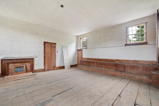 89 John Perry Rd, Eastford, CT 06242 - unfurnished living room featuring plenty of natural light, a brick fireplace, and hardwood / wood-style flooring