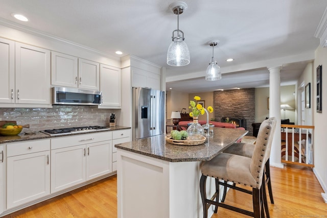 94 Southpond Rd, Glastonbury, CT 06073 - kitchen featuring appliances with stainless steel finishes, a stone fireplace, light wood-type flooring, a breakfast bar area, and white cabinetry