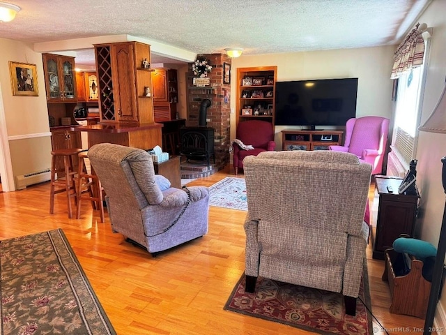 30 Cedar Ave, Wolcott, CT 06716 - living area featuring a wood stove, a textured ceiling, baseboard heating, light wood finished floors, and built in shelves