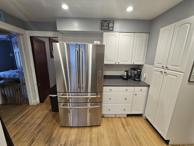 58 Waverly Pl, Bridgeport, CT 06610 - kitchen with freestanding refrigerator, dark countertops, light wood-style flooring, white cabinetry, and tasteful backsplash