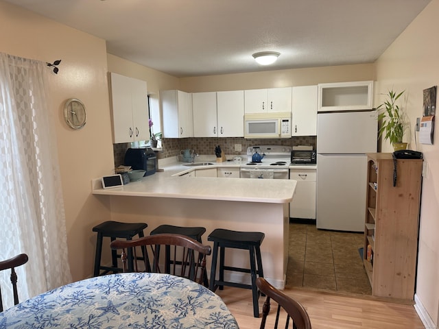 925 Oronoke Rd Unit 12G, Waterbury, CT 06708 - kitchen featuring white appliances, a sink, a breakfast bar, a peninsula, and tasteful backsplash