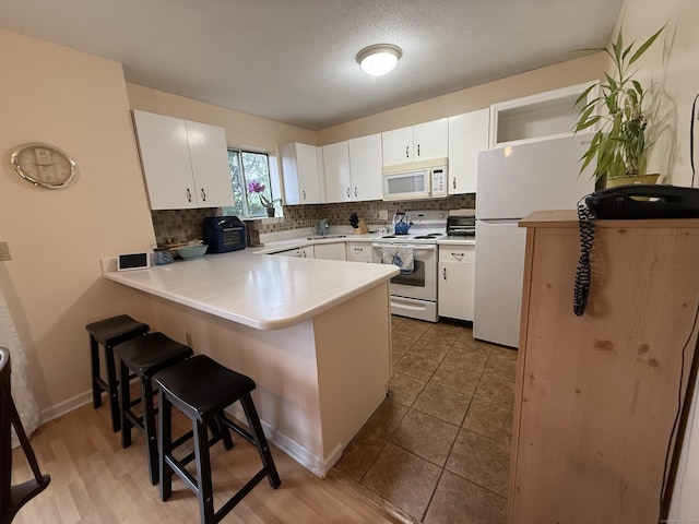 925 Oronoke Rd Unit 12G, Waterbury, CT 06708 - kitchen with white appliances, a peninsula, tasteful backsplash, a breakfast bar, and a textured ceiling