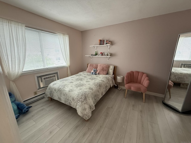 925 Oronoke Rd Unit 12G, Waterbury, CT 06708 - bedroom with a baseboard heating unit, an AC wall unit, light wood-style flooring, baseboards, and a textured ceiling