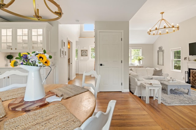 6 Lee Cir, Kent, CT 06757 - dining space featuring a chandelier, light wood-style flooring, vaulted ceiling, and a fireplace