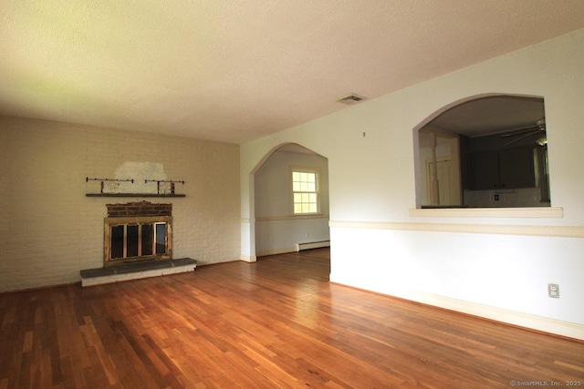 73 Devils Garden Rd, Norwalk, CT 06854 - unfurnished living room featuring baseboard heating, wood finished floors, a fireplace, ceiling fan, and arched walkways