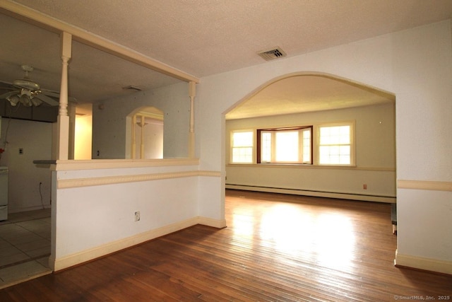 73 Devils Garden Rd, Norwalk, CT 06854 - empty room featuring a baseboard heating unit, arched walkways, ceiling fan, wood finished floors, and a textured ceiling
