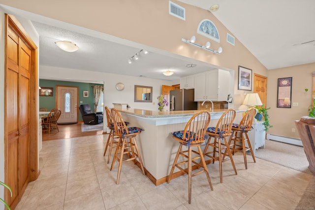 223 Beach Rd, Wolcott, CT 06716 - kitchen featuring a baseboard radiator, stainless steel fridge, light tile patterned floors, a peninsula, and a kitchen breakfast bar
