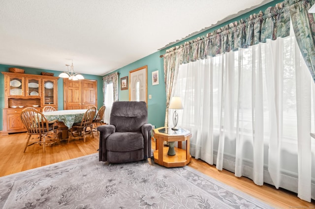 223 Beach Rd, Wolcott, CT 06716 - living room featuring wood finished floors, a chandelier, and a textured ceiling