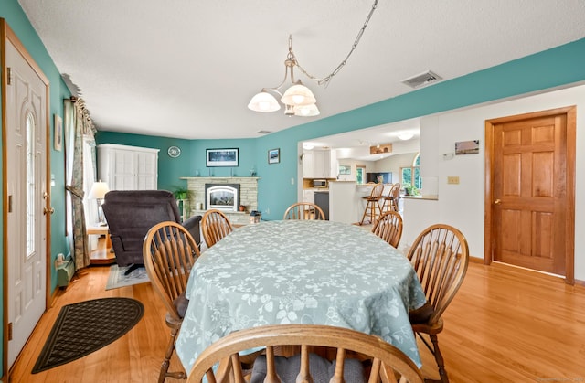 223 Beach Rd, Wolcott, CT 06716 - dining room with light wood-style floors, a chandelier, and a brick fireplace