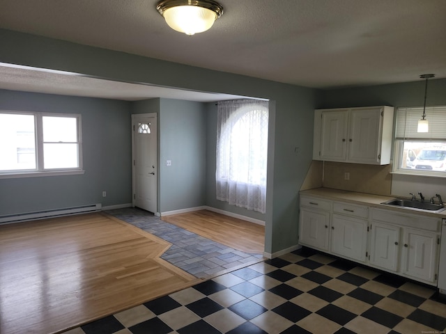 66 Macnamara St, Waterbury, CT 06708 - kitchen featuring a sink, a baseboard heating unit, healthy amount of natural light, white cabinetry, and a textured ceiling