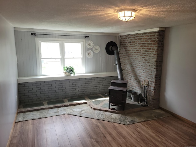 66 Macnamara St, Waterbury, CT 06708 - unfurnished living room featuring a wood stove, wood finished floors, and a textured ceiling