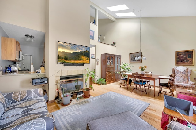 472 Carriage Dr Unit 472, Southington, CT 06489 - living area featuring high vaulted ceiling, a fireplace, a skylight, light wood finished floors, and a chandelier