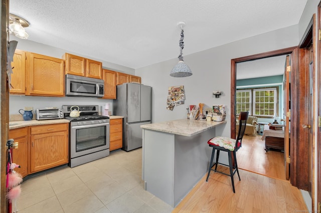 472 Carriage Dr Unit 472, Southington, CT 06489 - kitchen featuring stainless steel appliances, a kitchen bar, a peninsula, decorative light fixtures, and light stone counters