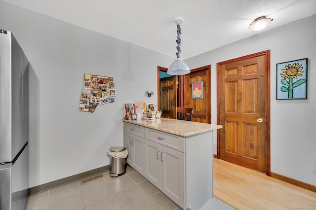 472 Carriage Dr Unit 472, Southington, CT 06489 - kitchen with a peninsula, baseboards, freestanding refrigerator, pendant lighting, and light stone countertops