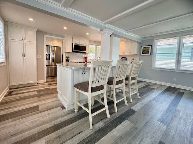 25 Milesfield Ave, Milford, CT 06460 - kitchen with appliances with stainless steel finishes, backsplash, a breakfast bar area, white cabinets, and wood finished floors