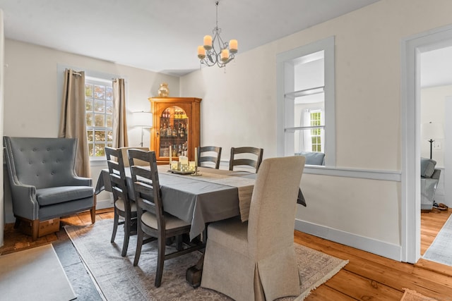 517 Wolcott Hill Rd, Wethersfield, CT 06109 - dining area with a chandelier, wood finished floors, and baseboards