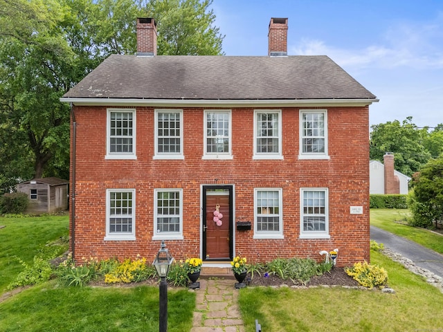 517 Wolcott Hill Rd, Wethersfield, CT 06109 - colonial house featuring a chimney, a front lawn, brick siding, and roof with shingles