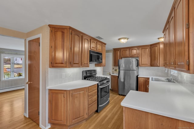 192 Hilton Dr, South Windsor, CT 06074 - kitchen featuring appliances with stainless steel finishes, a baseboard radiator, light wood-style flooring, backsplash, and light countertops