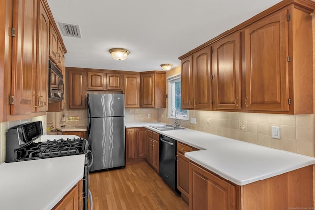 192 Hilton Dr, South Windsor, CT 06074 - kitchen with appliances with stainless steel finishes, a sink, light wood finished floors, brown cabinets, and decorative backsplash