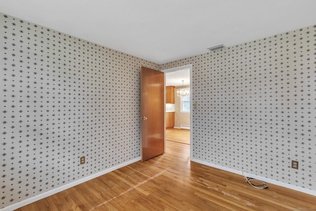 192 Hilton Dr, South Windsor, CT 06074 - empty room with baseboard heating, wallpapered walls, light wood-type flooring, a chandelier, and baseboards