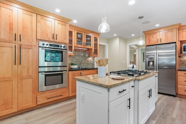 110 Florence Ln, Fairfield, CT 06824 - kitchen featuring appliances with stainless steel finishes, backsplash, light wood finished floors, glass insert cabinets, and a kitchen island