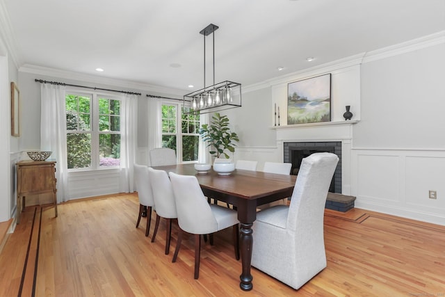 110 Florence Ln, Fairfield, CT 06824 - dining area featuring crown molding, a decorative wall, light wood-type flooring, a fireplace, and a chandelier