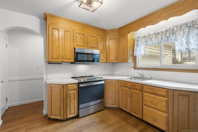 1897 Stanley St, New Britain, CT 06053 - kitchen with stainless steel appliances, a sink, light wood finished floors, light countertops, and arched walkways