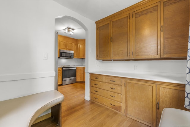 1897 Stanley St, New Britain, CT 06053 - kitchen with stainless steel appliances, light wood-type flooring, arched walkways, and light countertops