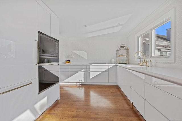 123 Harbor Dr Apt 403, Stamford, CT 06902 - kitchen featuring a sink, white cabinets, modern cabinets, and ornamental molding