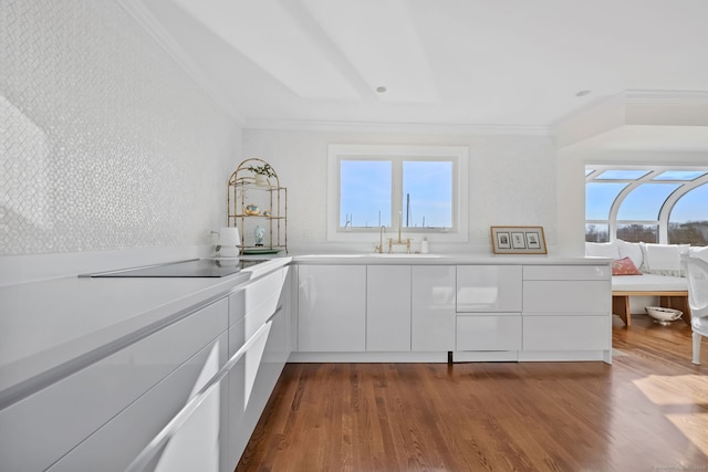 123 Harbor Dr Apt 403, Stamford, CT 06902 - kitchen featuring crown molding, a sink, black electric stovetop, light countertops, and white cabinetry
