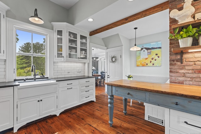 131 Elm St, Guilford, CT 06437 - kitchen with dark countertops, a sink, glass insert cabinets, decorative backsplash, and beamed ceiling