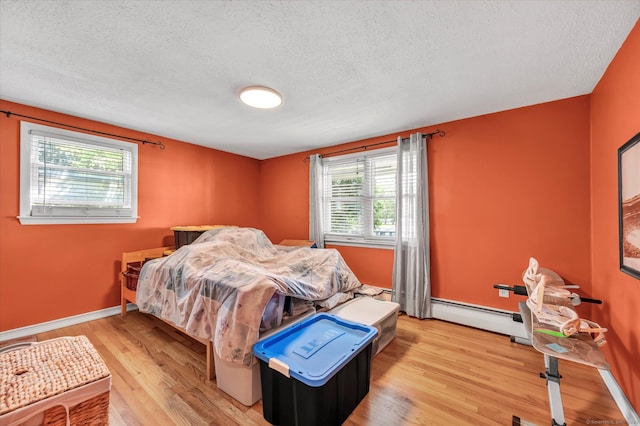 70 Birchwood Dr, Middletown, CT 06457 - bedroom with a baseboard radiator, a textured ceiling, light wood finished floors, and baseboards