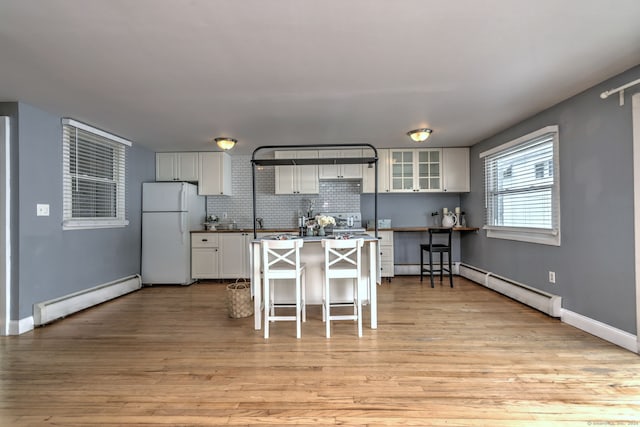 190 Wooster St Unit 27, New Haven, CT 06511 - kitchen with a baseboard radiator, freestanding refrigerator, a breakfast bar area, and white cabinets