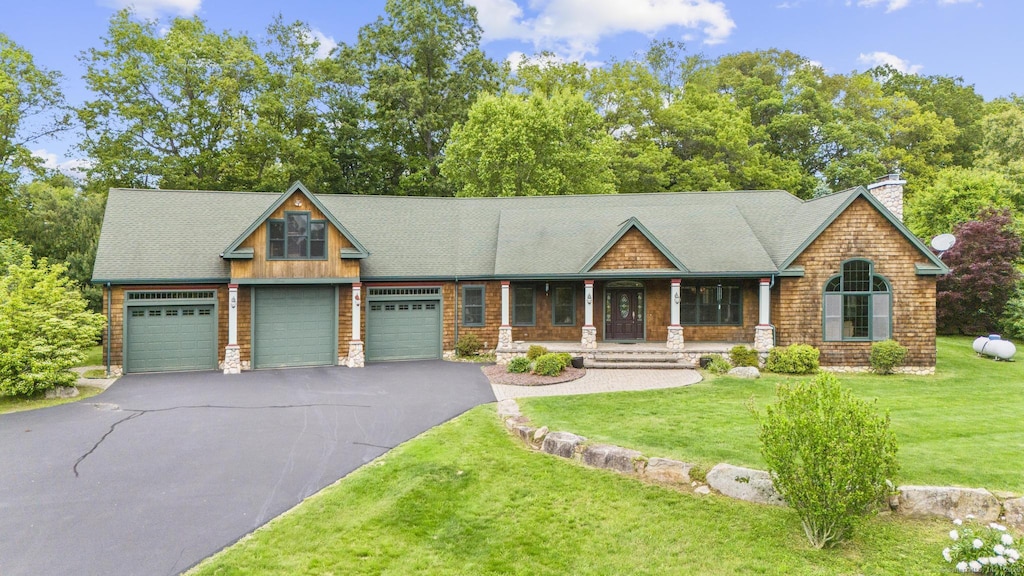 55 Paula Ln, Manchester, CT 06040 - view of front of home featuring covered porch, a front lawn, driveway, and a garage