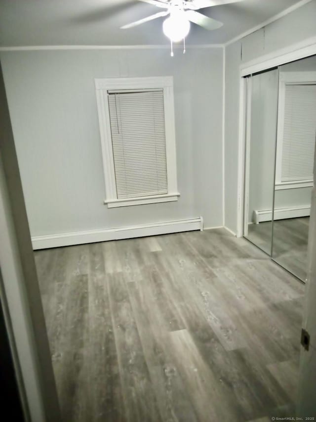 100 Roosevelt Ave, Torrington, CT 06790 - unfurnished bedroom featuring a baseboard radiator, wood finished floors, a closet, a ceiling fan, and baseboard heating