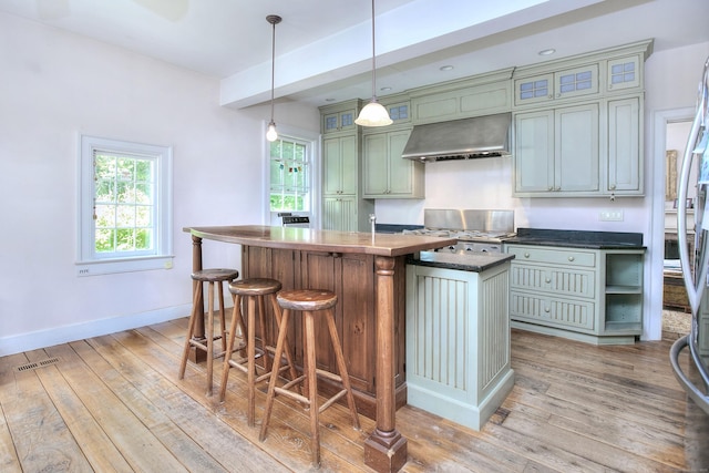 587 Carter St, New Canaan, CT 06840 - kitchen with extractor fan, range, light wood-type flooring, dark countertops, and an island with sink