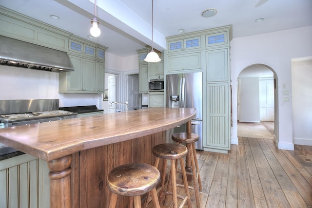 587 Carter St, New Canaan, CT 06840 - kitchen with appliances with stainless steel finishes, wall chimney exhaust hood, arched walkways, a breakfast bar, and pendant lighting