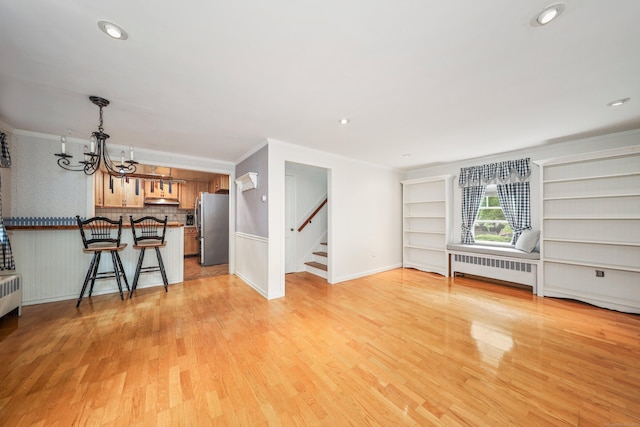 70 Cold Spring Cir, Naugatuck, CT 06770 - unfurnished living room with radiator heating unit, a chandelier, light wood-style flooring, stairway, and crown molding
