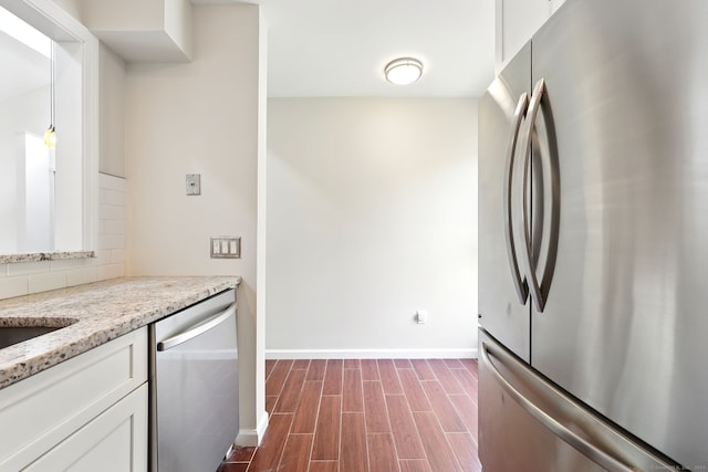 27 Pheasant Run Unit 27, Cromwell, CT 06416 - kitchen featuring appliances with stainless steel finishes, white cabinetry, baseboards, light stone counters, and dark wood-style flooring
