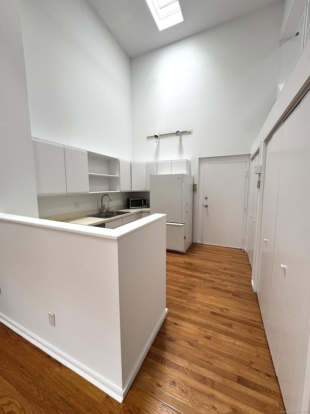 32 Pine St Unit 12Aka 15, Norwalk, CT 06854 - kitchen featuring freestanding refrigerator, a sink, stainless steel microwave, open shelves, and a skylight