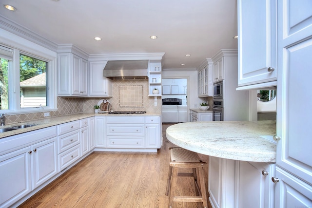52 Woodside Ave, Westport, CT 06880 - kitchen with exhaust hood, appliances with stainless steel finishes, white cabinetry, light wood-style floors, and ornamental molding