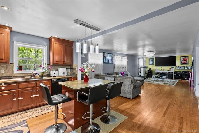 146 Whitewood Rd, Torrington, CT 06790 - kitchen featuring black dishwasher, a sink, a center island, light wood finished floors, and decorative backsplash