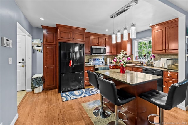 146 Whitewood Rd, Torrington, CT 06790 - kitchen with black appliances, light wood-type flooring, backsplash, a breakfast bar, and decorative light fixtures
