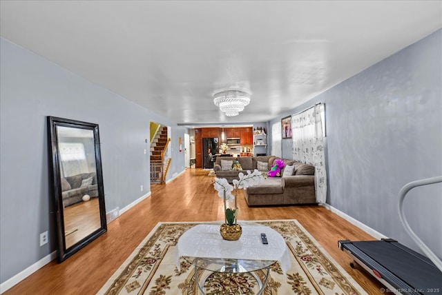 146 Whitewood Rd, Torrington, CT 06790 - living room with a chandelier, light wood-style floors, stairs, and baseboards
